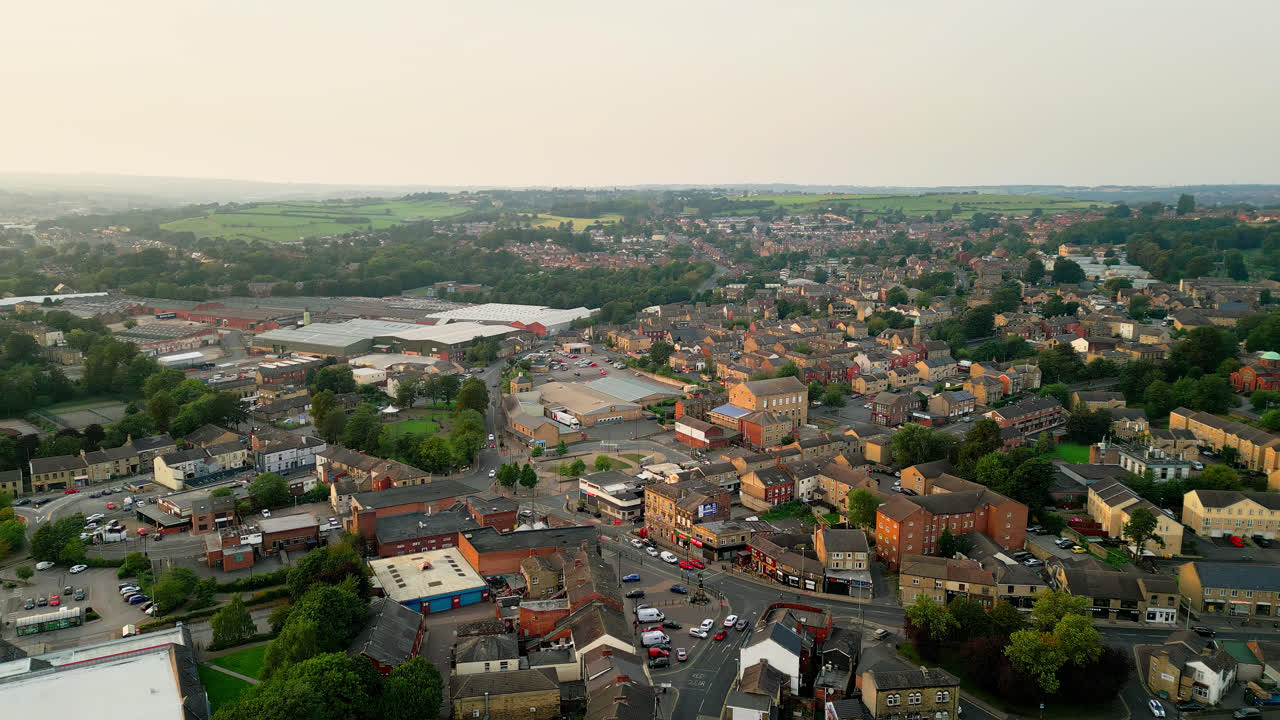 un avión no tripulado registra heckmondwike, reino unido, con edificios industriales, calles bulliciosas y el centro antiguo de la ciudad en una noche de verano
