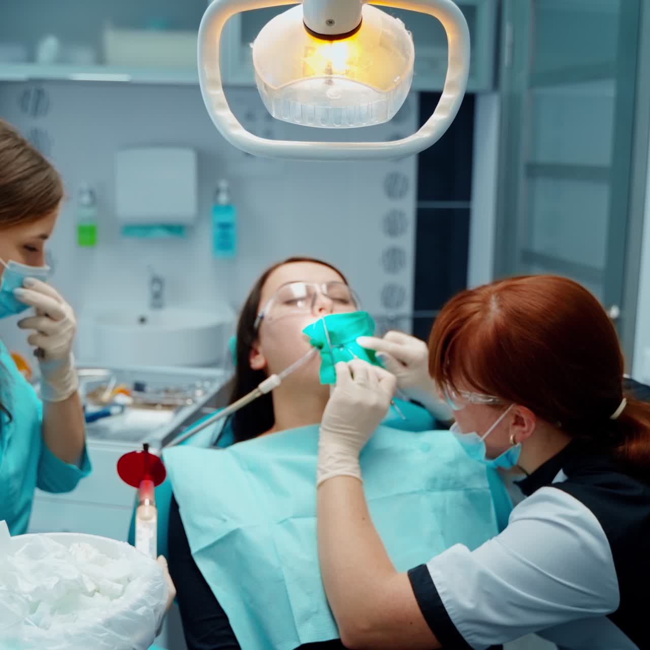 Female dentist treating teeth to female patient. Woman sitting with open mouth at dentistry. Medical staff working in modern stomatology clinic.