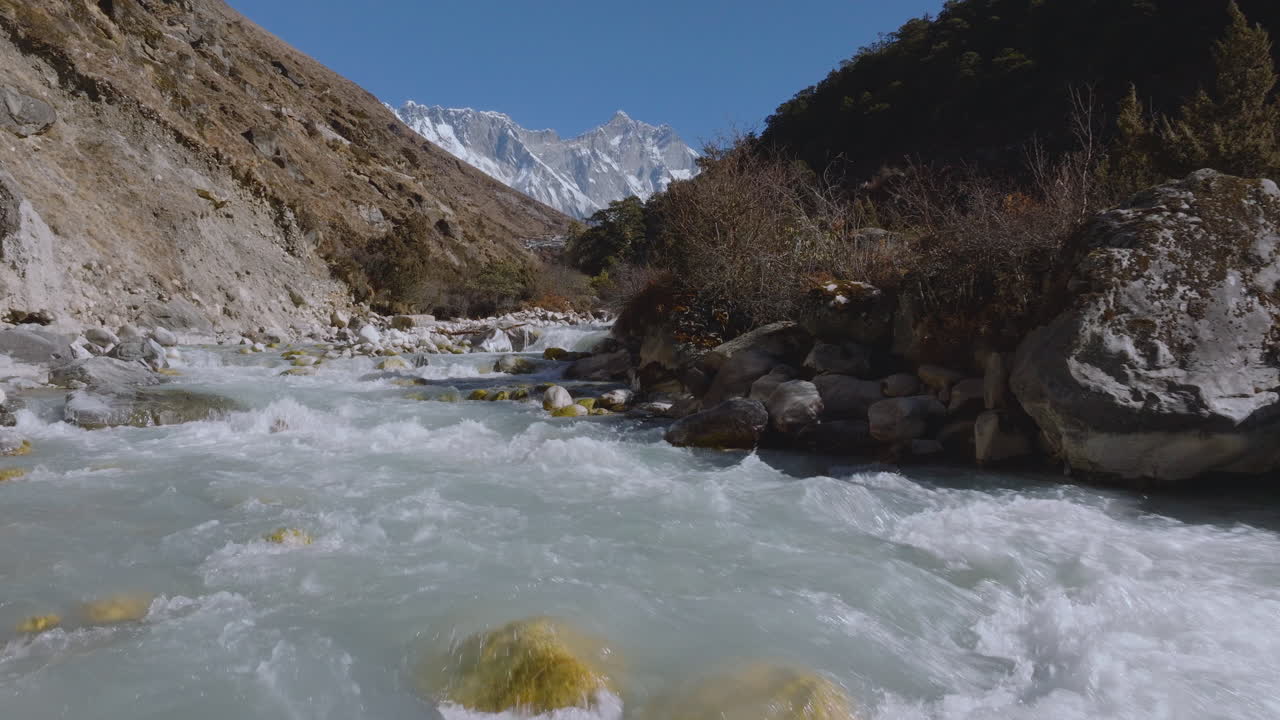 Scenic view of fresh blue water flowing through the Dudh Koshi River in the Khumbu region of Nepal. Glacial river sourced from the melting Khumbu Glacier, highlighting the Himalayan ecosystem