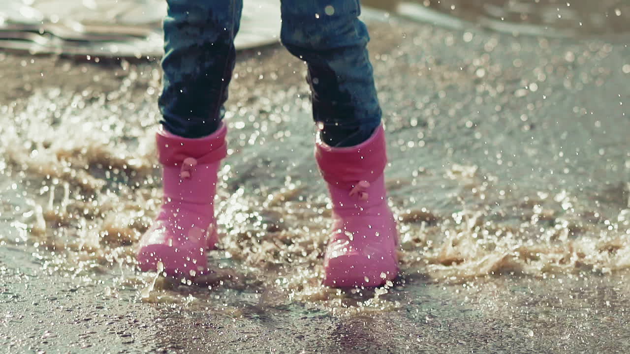 little child runs and jumps into deep puddle