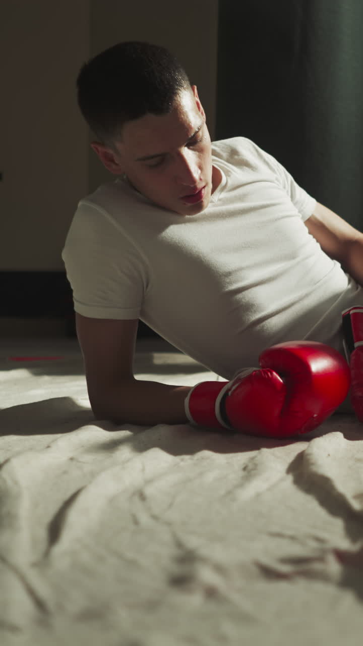 boxeador calmo en guantes de boxeo yace en el suelo del gimnasio descansando después de un trabajo intensivo para mejorar la fuerza y la forma del cuerpo. relajación después de practicar deportes de lucha en el club