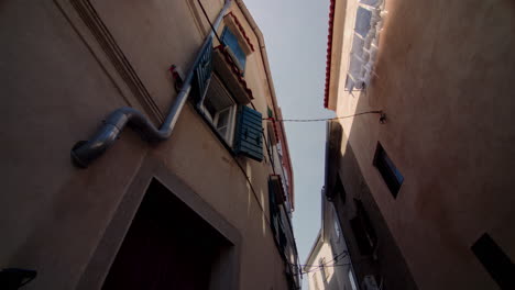 Upward-pan-across-open-windows-in-shaded-alleyway-from-building-facade-in-Europe