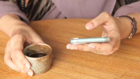 전화 를 사용 하고 테이블 에서 커피 를 마시는 여자