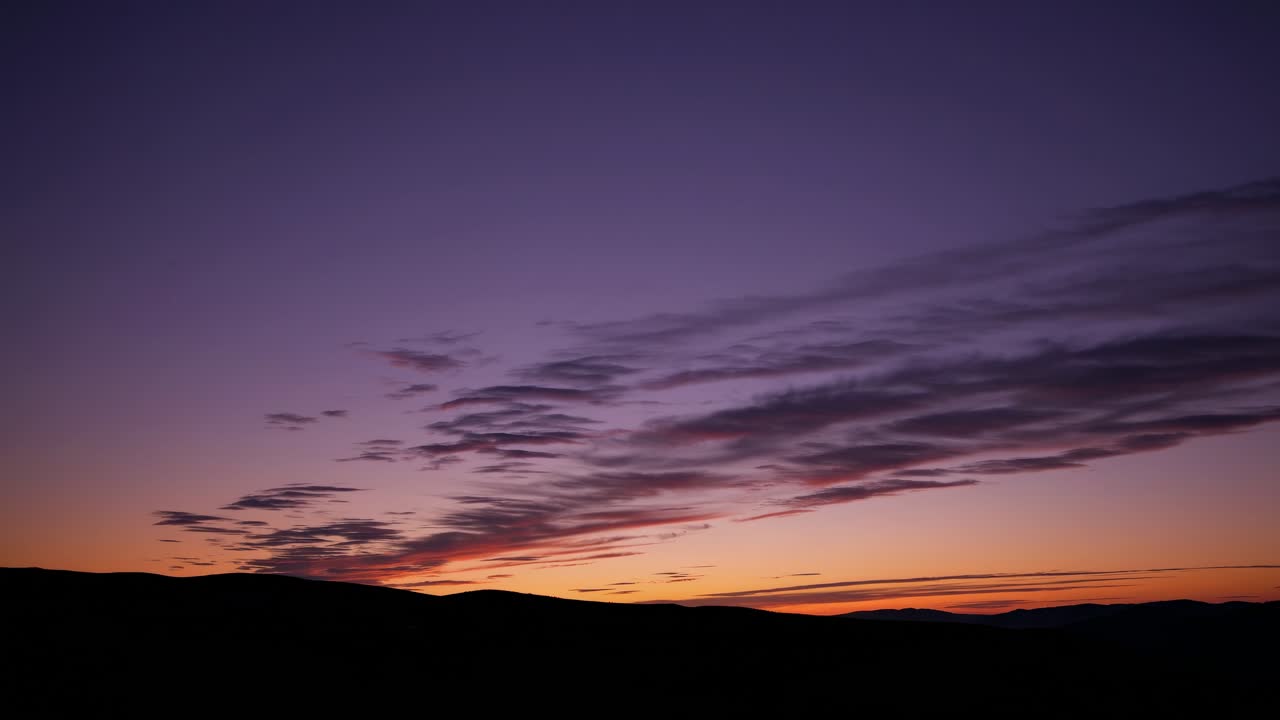 A serene sunset video captures a wide-angle view of silhouetted hills under a gradient sky