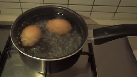 boiling two eggs in a saucer pan on a stove