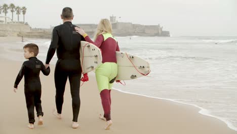 family with surfboards walking on beach