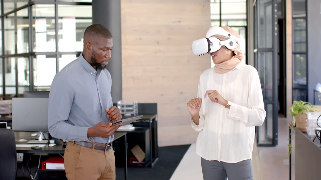 Using VR headset, woman interacting with virtual environment, man holding tablet