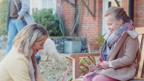 grandmother helping granddaughter to tie shoelaces as they get ready to go on walk with pet dog