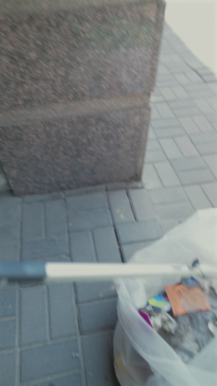 persona que utiliza una herramienta para limpiar el contenedor de reciclaje