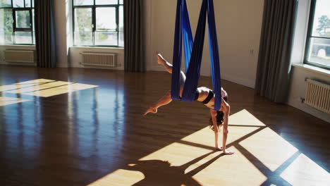 woman practicing aerial yoga in a studio