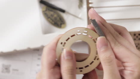 mano femenina lijando artesanía en madera circular con papel de lija en el taller