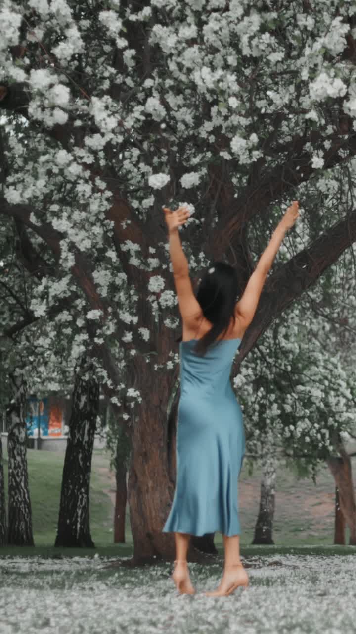 Woman in a blue dress enjoying a spring day in a blooming park
