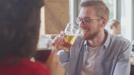 smiling young couple on date enjoying pizza in restaurant together making a toast