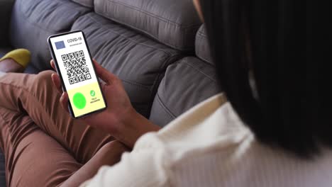 mujer en casa con un teléfono inteligente con certificado de vacunación contra la covid, bandera de la ue y código qr en la pantalla