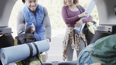 Happy-african-american-couple-taking-backpacks-from-car-trunk,-slow-motion