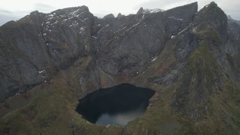 vista aérea de un lago entre montañas en lofoten, noruega - tire hacia atrás, tiro de drones