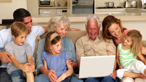 familia extendida usando computadora portátil juntos en el sofá