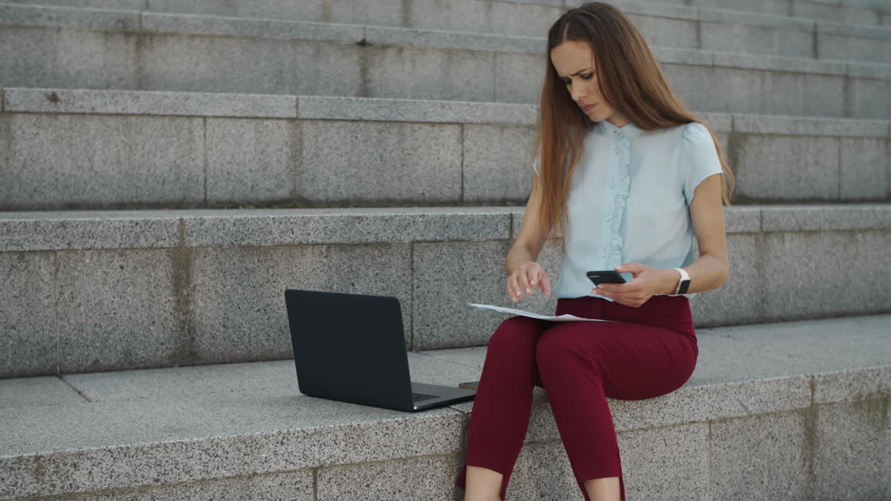 Upset businesswoman taking photo of documents on smartphone in modern city
