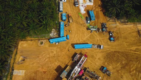 Cinematic-Drone-Footage-of-Onshore-Drilling-Rig-equipment-structure-for-oil-exploration-and-exploitation-in-the-middle-of-jungle-surrounded-by-palm-oil-trees-during-sunset-and-high-oil-price