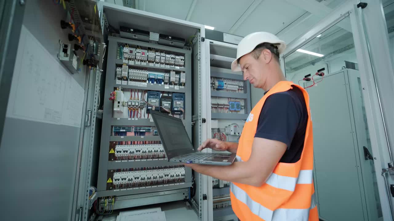 el ingeniero eléctrico que trabaja comprueba la tensión de corriente eléctrica y la sobrecarga en la parte delantera del gabinete del centro de carga o de la unidad de consumo para el mantenimiento en la sala principal del sistema de distribución de energía.