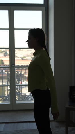 woman in profile view standing by a window