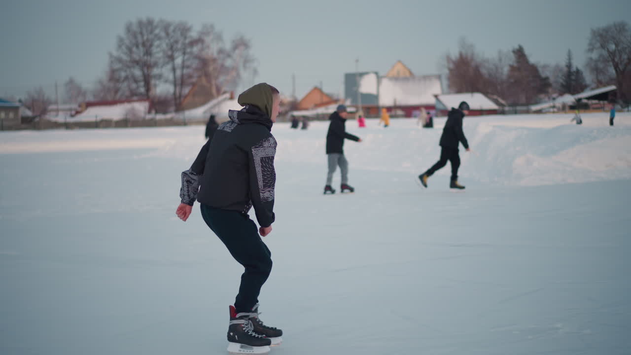 hockey players skating on frozen lake near snowy banks with residential houses in scene, wearing winter jackets and helmets, informal ice hockey game with sticks on smooth ice under clear sky