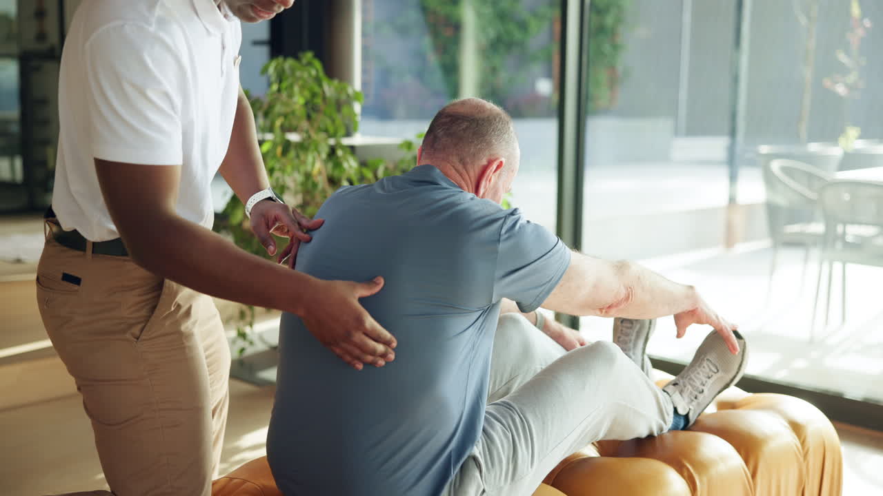 Physical Therapist Assisting Senior Man with Back Stretching Exercise