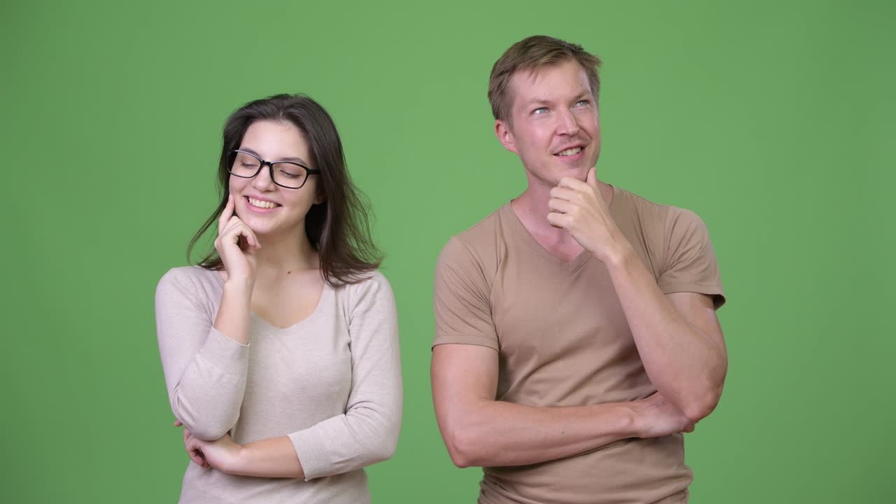Young happy couple thinking together against green background