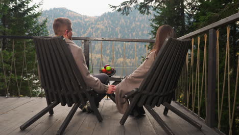 romantic couple sitting on a deck overlooking a mountain lake