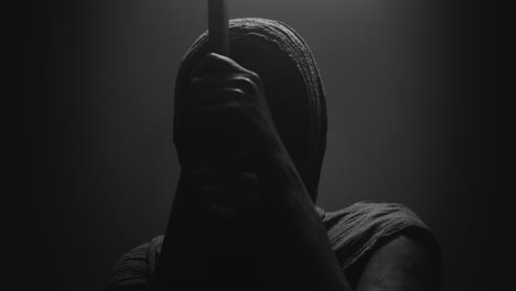 a mummified woman against the dark background pose with the walking staff