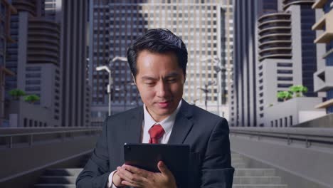 an asian business man smiling while using tablet in city