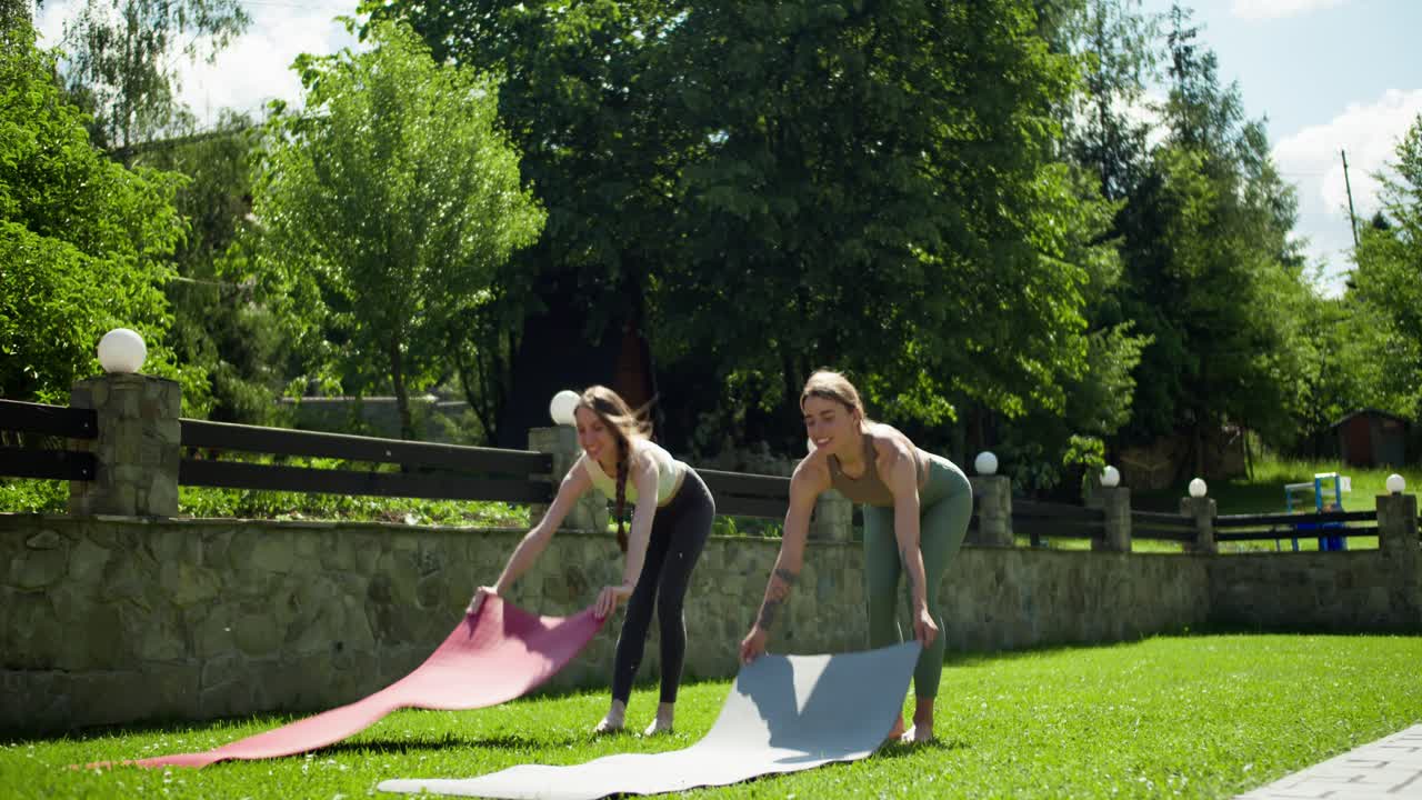 2 chicas rubias en un uniforme especial de deportes de verano ponen esteras especiales de yoga y se preparan para deportes al aire libre