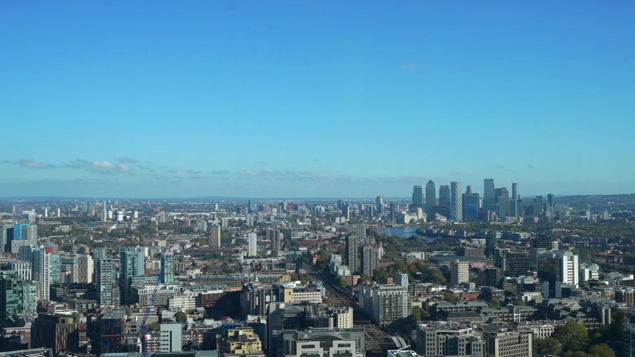 澄み切った青空の下、都市建築とカナリーワーフが広がるロンドンのパノラマ風景