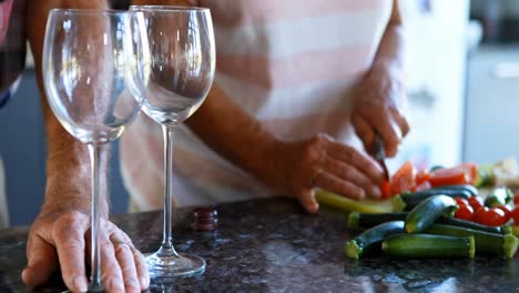 Senior-couple-chopping-vegetables-while-having-wine-4k