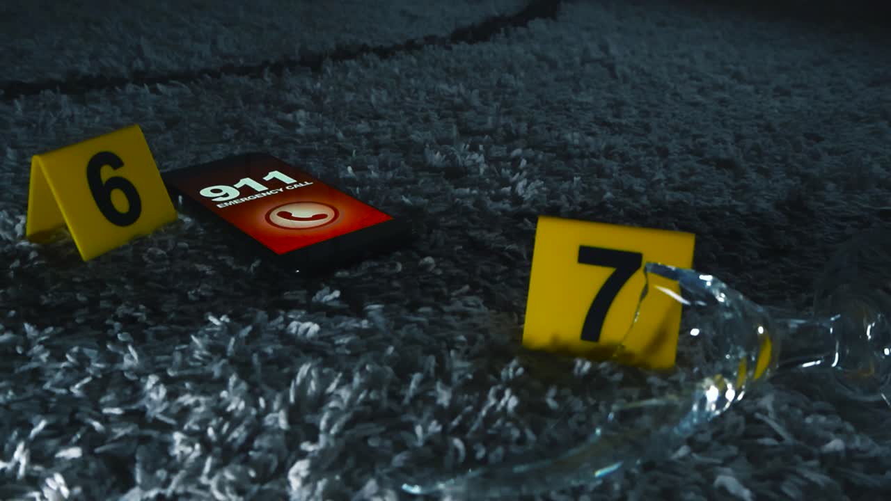 Close up view of a broken beer or a wine glass and a phone dialing and calling 911 emergency number next to yellow colored and numbered police investigation crime scene markers on carpet indoors