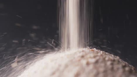 video of close up of sand grains pouring into heap and copy space on black background