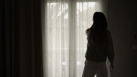 woman opening curtains in hotel room going out on the balcony, pulling hands up