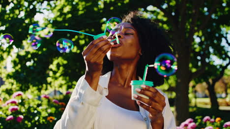 joyful young woman blowing bubbles in a sunny park