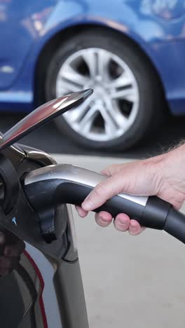 persona conecta el cargador al vehículo eléctrico