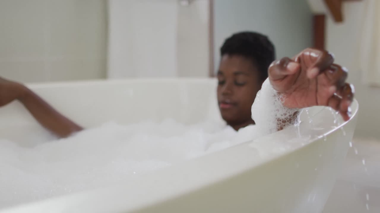 Hands of african american attractive woman relaxing in foam bath in bathroom