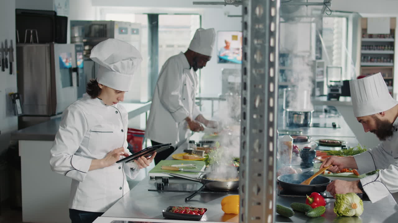 Authentic chef looking at food recipe on digital tablet screen