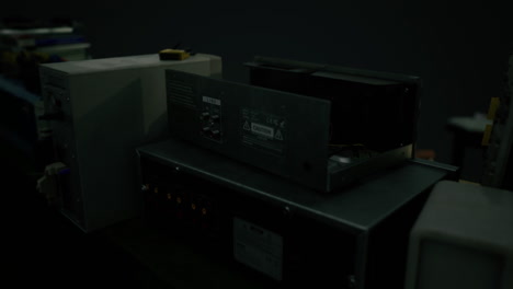 old electronic equipment stacked together in a dimly lit workshop