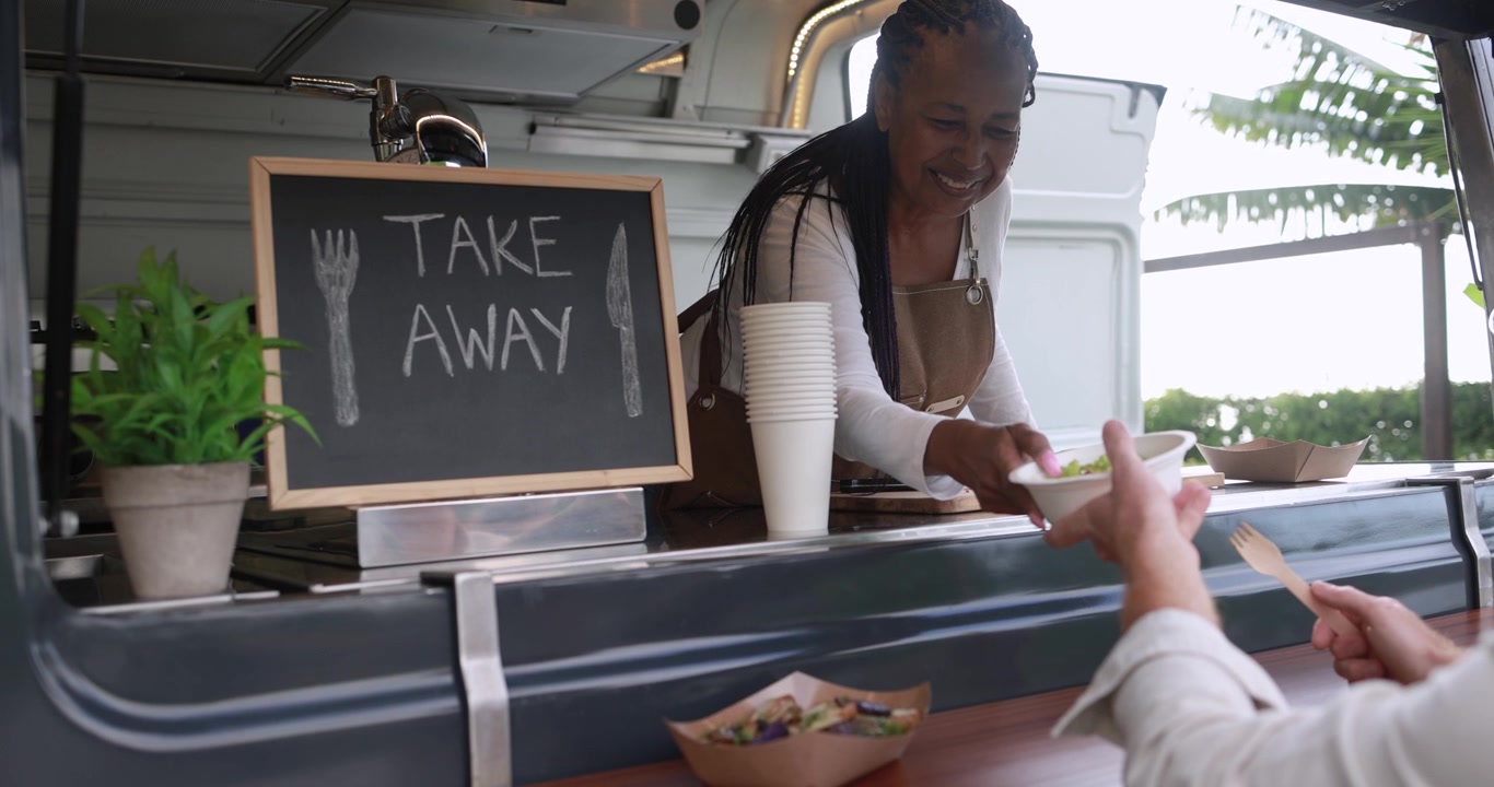 Happy African American Woman Serving Food to Customer in Food Truck