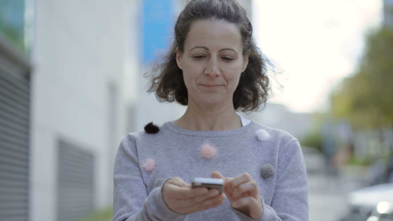 vista frontal de una mujer de mediana edad sonriente usando un teléfono inteligente.