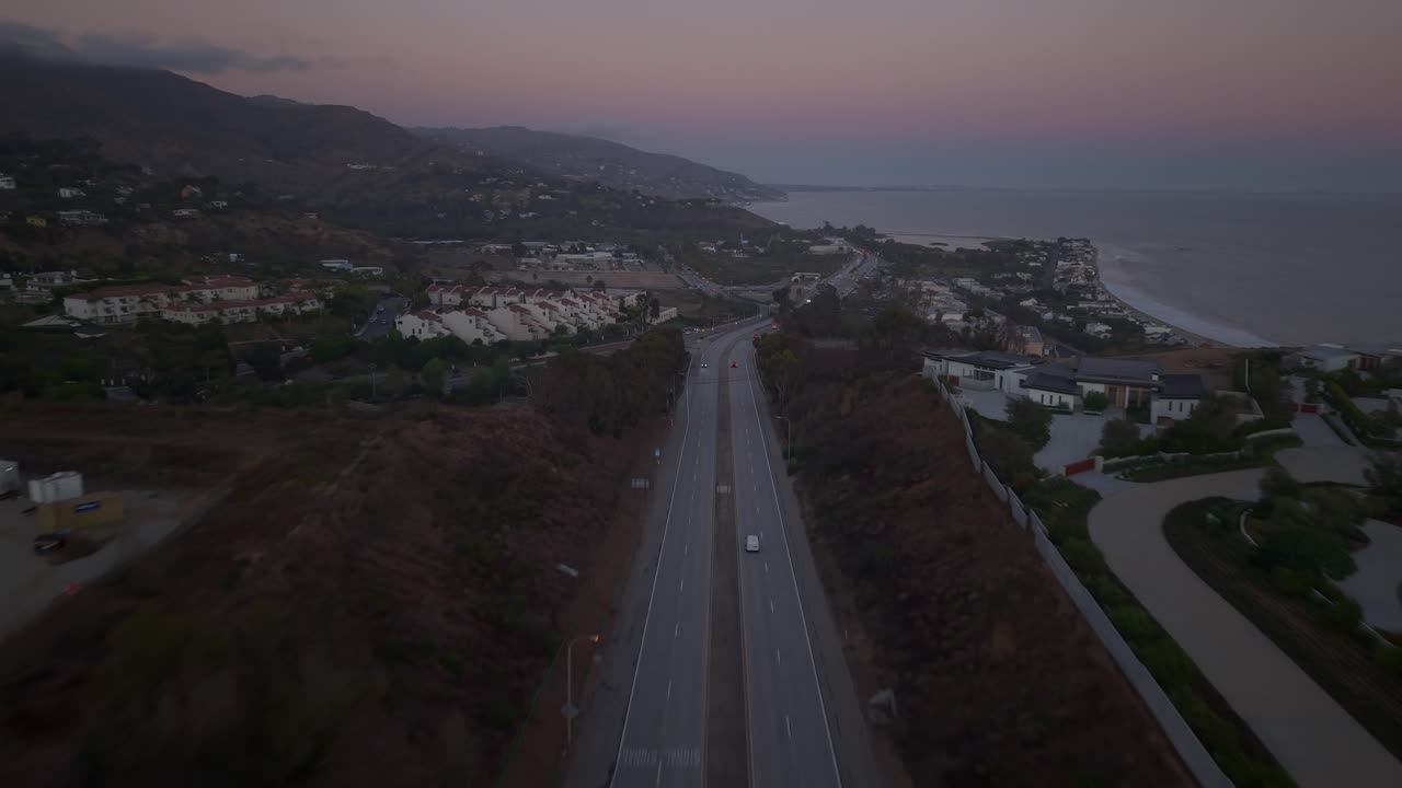 Cars Driving on Pacific Coast Highway and the coastal mountains behind. Looking South towards Downtown Malibu, Santa Monica and Long Beach California