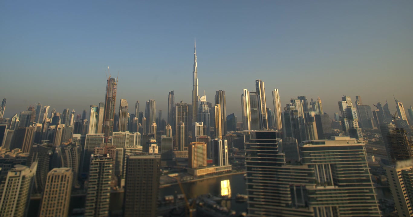 Timelapse dell'iconico skyline di Dubai con il Burj Khalifa e moderni grattacieli sotto un cielo azzurro e limpido durante la luce del tardo pomeriggio