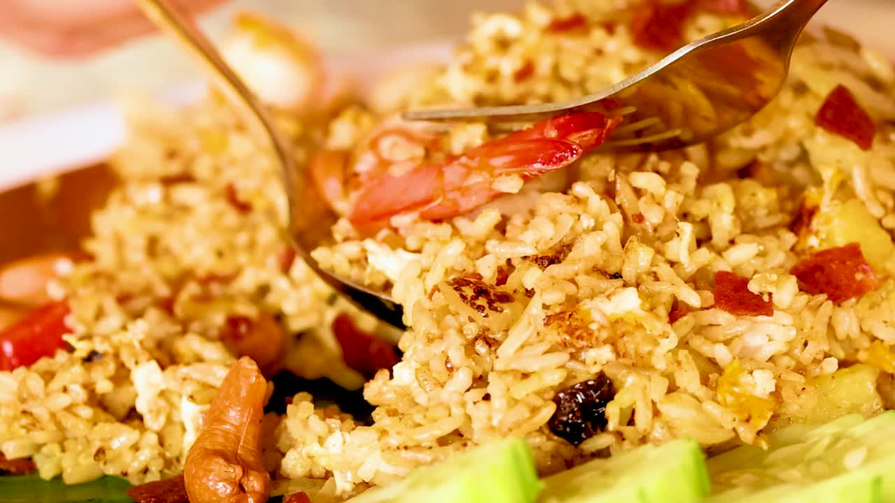 Detailed view of shrimp fried rice being served with a fork and spoon, highlighting vibrant ingredients.