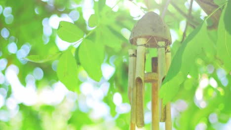 wooden windchime hanging on a tree with green leaves in summer