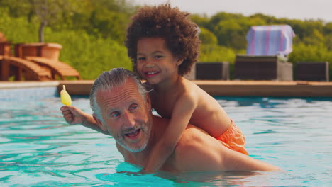 Abuelo-Jugando-Con-Su-Nieto-Comiendo-Polo-De-Hielo-En-La-Piscina-Durante-Las-Vacaciones-Familiares-De-Verano