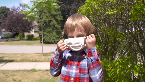 cute little boy putting on a mask to protect against coronavirus